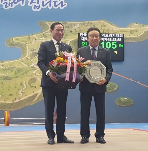 This undated photo provided by the Korea Weightlifting Federation (KWF) shows Yanggu County Gov. Jeon Chang-beom (R) receiving an award with KWF President Lee Won-sung. (Yonhap)