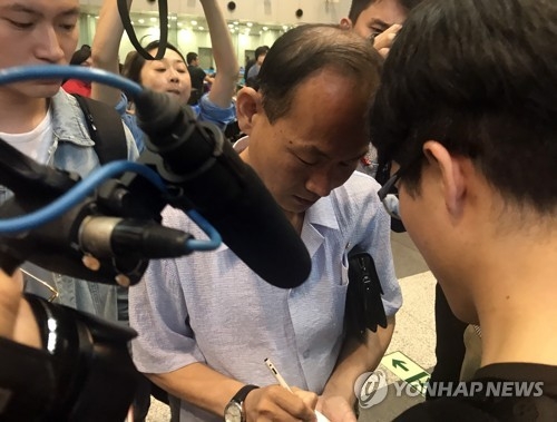 Won Jong-hyok (C), a Beijing correspondent for North Korea's Rodong Sinmun, speaks with reporters at Beijing Capital International Airport on May 22, 2018. (Yonhap)