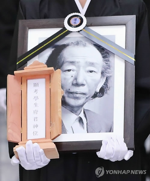 A family member of writer Choi In-hun carries his portrait during a funeral on July 25, 2018. (Yonhap)