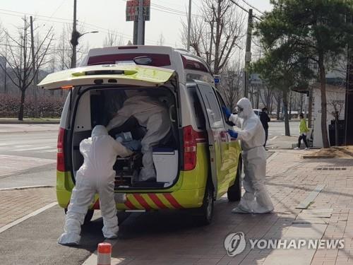 Health workers transfer a novel coronavirus patient at a nursing hospital in Gyeongsan, North Gyeongsang Province, on March 21, 2020. (Yonhap)