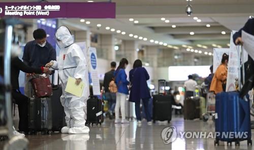 This photo taken on May 3, 2020, shows a health official speaking with a tourist at Incheon International Airport in Incheon, west of Seoul. (Yonhap)