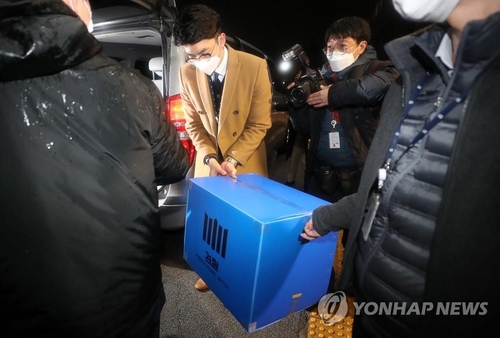 Investigators carry a box of documents out of the Ministry of Justice after making a raid into the ministry in connection with an investigation into an allegedly illegal overseas travel ban on Kim Hak-ui, a former vice justice minister, in Gwacheon, south of Seoul, on Jan. 21, 2021. (Yonhap)