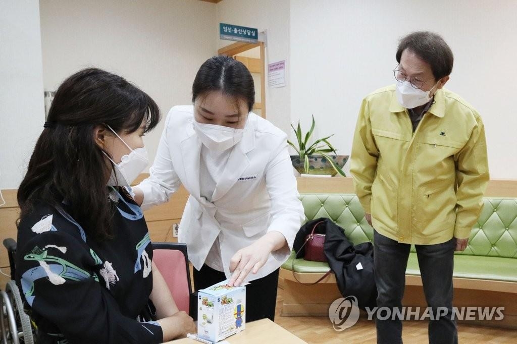 Cho Hee-yeon, superintendent of the Seoul Metropolitan Office of Education, watches a school nurse getting a vaccine shot at a community health center in Seoul on April 13, 2021. (Yonhap)