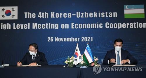 South Korean Deputy Prime Minister for Economy Hong Nam-ki (L) and his Uzbek counterpart, Sardor Umurzakov, sign minutes at the fourth Korea-Uzbekistan High-level Meeting on Economic Cooperation at a Seoul hotel on Nov. 26, 2021. (Yonhap)