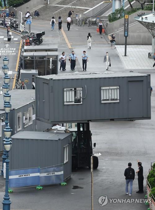 Workers remove a container building used as a makeshift clinic for coronavirus tests in front of Seoul Station on July 1, 2022, as South Korea has seen COVID-19 cases declining. (Yonhap)