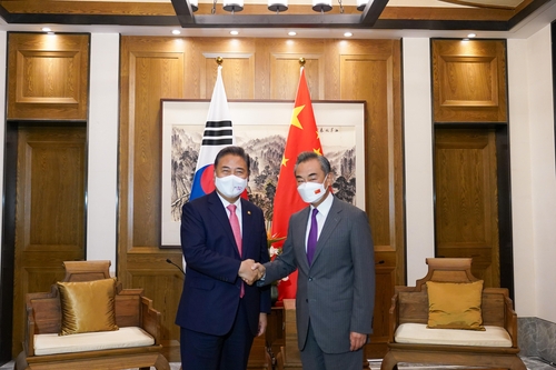 South Korean Foreign Minister Park Jin (L) and his Chinese counterpart, Wang Yi, shake hands during a meeting in the eastern Chinese port city of Qingdao on Aug. 9, 2022, in this photo provided by Seoul's foreign ministry. (PHOTO NOT FOR SALE) (Yonhap)