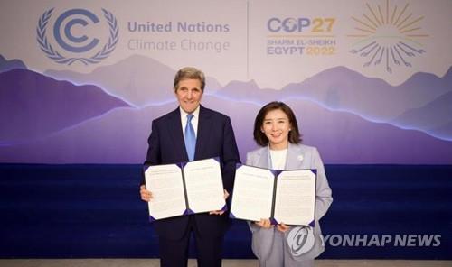This photo, provided by Seoul's oceans ministry, shows South Korea's climate ambassador, Na Kyung-won (R), and U.S. climate envoy John Kerry posing for a photo in Egypt on Nov. 8, 2022, after signing an agreement on the creation of a green cargo shipping corridor. (PHOTO NOT FOR SALE) (Yonhap)