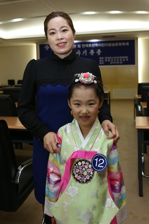 '제12회 홈타민컵 전국 조선족어린이 방송문화 축제'의 이야기경연에서 금상을 차지한 녕안시조선족소학교 진재여 학생과 지도교사 김영희 씨