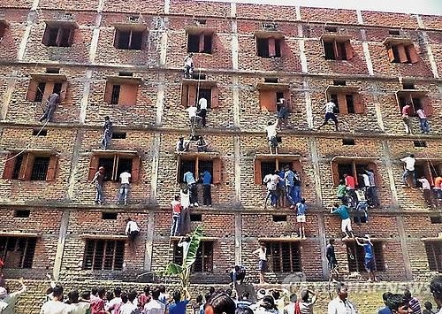 2015년 3월 인도 비하르 주 하지푸르의 한 고교입학자격시험 고사장에서 학부모들이 자녀에게 '커닝페이퍼'를 전달하려고 건물을 타고 오르고 있다.(AP/PTI=연합뉴스 자료사진)