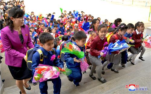 (평양 조선중앙통신=연합뉴스) 2018년 4월 3일 북한 평양 시내 한 소학교 입학식에서 꽃다발을 든 신입생들이 선생님과 함께 교실로 향하고 있다. 