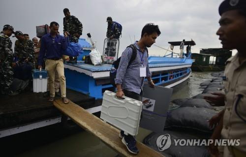 인도 동부 아삼주에서 배를 타고 투표 용품을 옮기는 선관위 직원들. [EPA=연합뉴스]