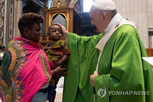 프란치스코 교황이 8일 바티칸 성베드로 대성당에서 난민과 이민자를 위한 미사를 집전한 뒤 이민자 가정의 아이를 쓰다듬고 있다. [AFP=연합뉴스] 