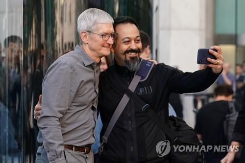 팀 쿡 애플 CEO가 20일(현지시간) 미국 뉴욕 5번가 애플 플래그십 매장 앞에서 고객과 셀카를 찍고 있다. [로이터=연합뉴스]