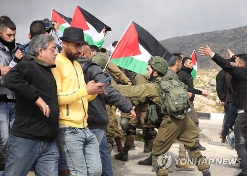 29일(현지시간) 요르단강 서안에서 팔레스타인 시위대와 이스라엘 군인들이 몸싸움을 하고 있다.[EPA=연합뉴스]