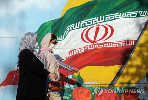 이란 국기가 그려진 벽화앞을 지나가는 테헤란 시민