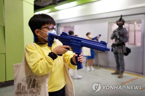15일 홍콩 '국가안보 교육의 날'에 홍콩 경찰대를 견학온 아이들이 지하철 모형 옆에서 장난감 총을 들고 노는 모습. [로이터=연합뉴스]