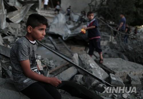 이스라엘의 공습으로 완전히 붕괴한 집 잔해에 주저앉은 팔레스타인 소년