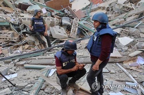 이스라엘군의 폭격으로 무너진 외신 입주 건물 잔해에 주저 앉은 취재진