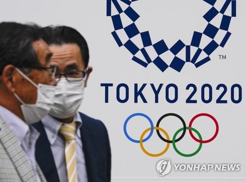 (도쿄 EPA=연합뉴스) 지난달 28일 일본 도쿄도(東京都)에서 마스크를 쓴 남성이 도쿄올림픽 홍보물 앞을 지나고 있다.