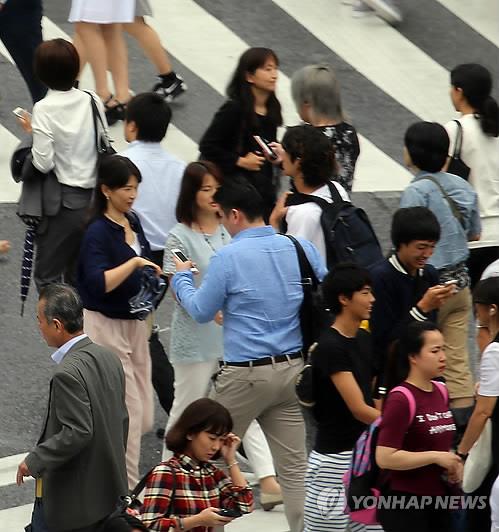 스마트폰 사용하며 걷는 도쿄의 보행자