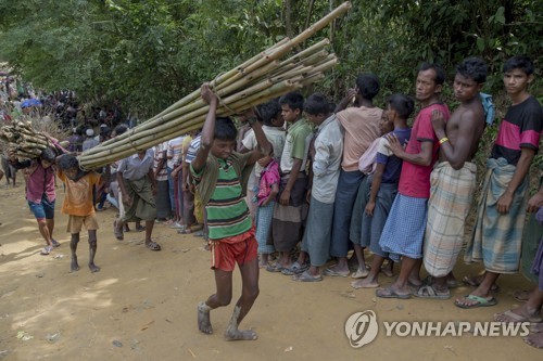 22일 방글라데시 쿠투팔롱에서 로힝야족 난민 소년들이 임시 거주시설을 만들기 위해 대나무를 옮기고 있다.[AP=연합뉴스 자료사진]