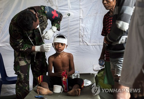 2018년 8월 5일 규모 7.0의 강진으로 대규모 인명피해가 발생한 이네시아 롬복섬에서 8일 군의관이 다친 소년을 치료하고 있다. [AP=연합뉴스 자료사진]