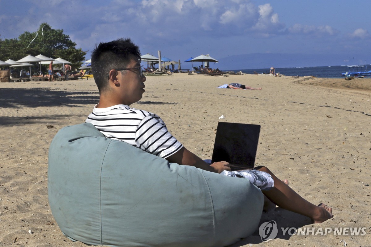 발리 해변에서 노트북으로 작업하는 중국인