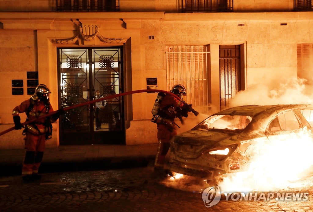 5일(현지시간) 프랑스 파리 거리에서 열린 '노란 조끼' 시위 중 소방관들이 자동차에 난 불을 끄려고 하고 있다. [AFP=연합뉴스]