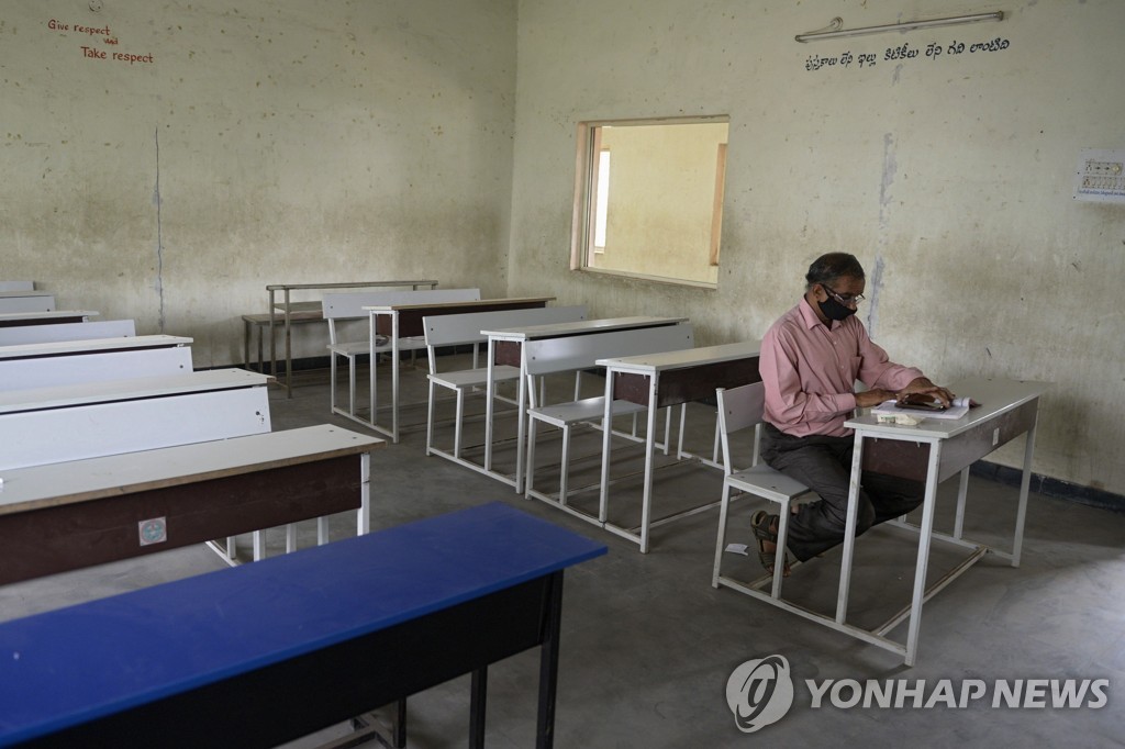 지난 21일(현지시간) 인도 안드라프라데시주의 한 학교의 텅 빈 교실에 교사가 홀로 앉아 있다.[AFP=연합뉴스]