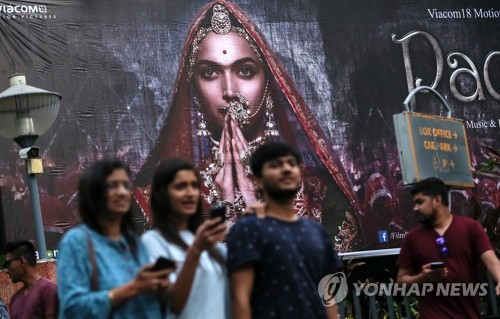 21일 인도 서부 뭄바이에서 힌두 여왕과 이슬람 왕의 로맨스를 묘사했다는 이유로 개봉이 무기한 연기된 영화 파드마바티 포스터 앞에 시민들이 지나가고 있다.[EPA=연합뉴스 자료사진]