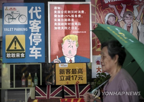 13일 중국 광저우에서 트럼프 포스터 앞으로 행인이 지나가고 있다. (EPA=연합뉴스)