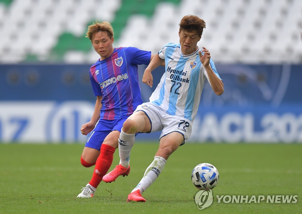 In this EPA photo, Lee Chung-yong of Ulsan Hyundai FC (R) tries to fend off Shuto Abe of FC Tokyo during their Group F match at the Asian Football Confederation Champions League at Education City Stadium in Al Rayyan, Qatar, on Nov. 30, 2020. (Yonhap)