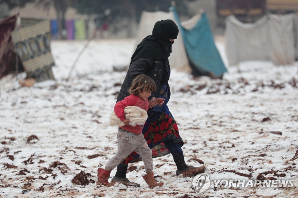  이달 14일 눈 내린 시리아 북서부의 피란민 캠프에서 이동하는 여성과 어린이