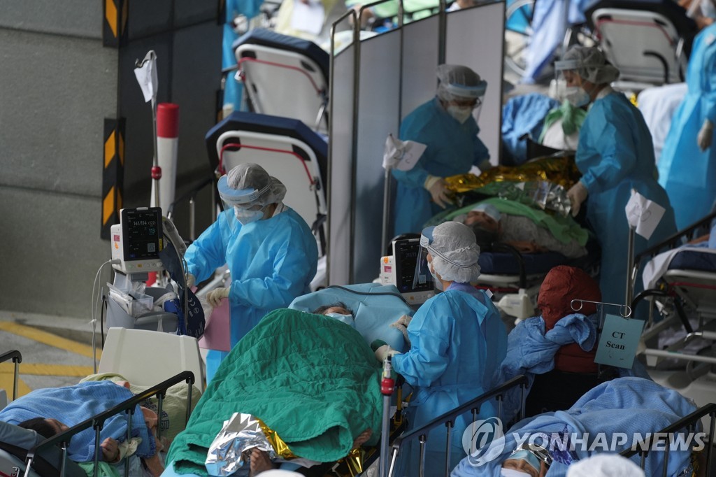 (로이터=연합뉴스) 17일 홍콩의 한 병원 바깥에서 대기 중인 코로나19 환자들을 의료진이 돌보는 모습. 