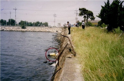 2002년 부산 강서구 바닷가에서 발견된 피해자 시신이 담긴 마대 자루. (빨간색 원)