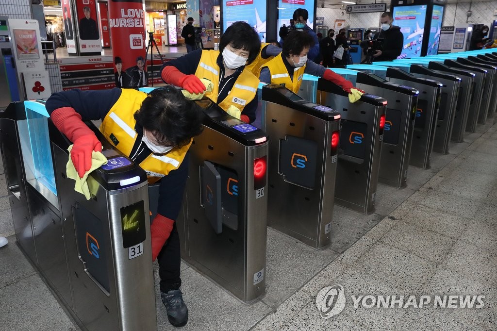 This photo, taken on March 4, 2020, shows janitors cleaning subway ticket gates at Myeongdong Station in central Seoul in a precautionary measure against the new coronavirus. The city government plans to adopt contactless gates so that passengers will not have to tag their cards at the ticket gates. (Yonhap)