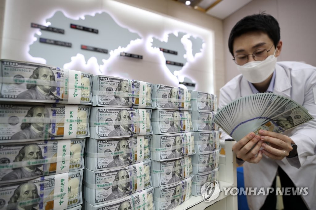 In the photo, taken April 27, 2020, a Hana Bank official inspects U.S. banknotes at a Seoul branch office. (Yonhap)