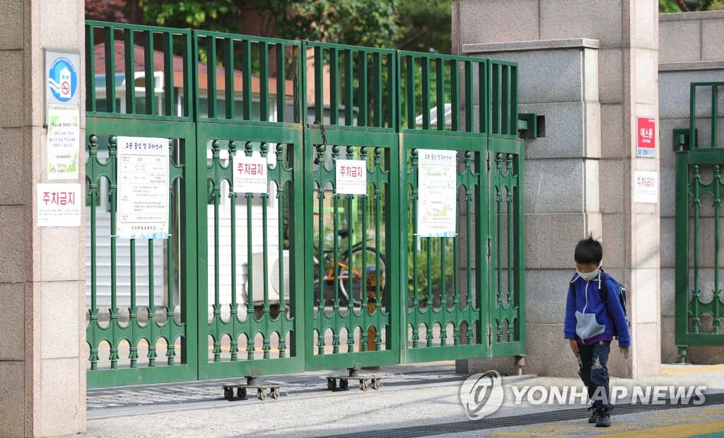 This May 28, 2020, photo shows a child walking past the entrance of an elementary school in Incheon, west of Seoul, that has been closed after a spike in new coronavirus infections in the area. (Yonhap)