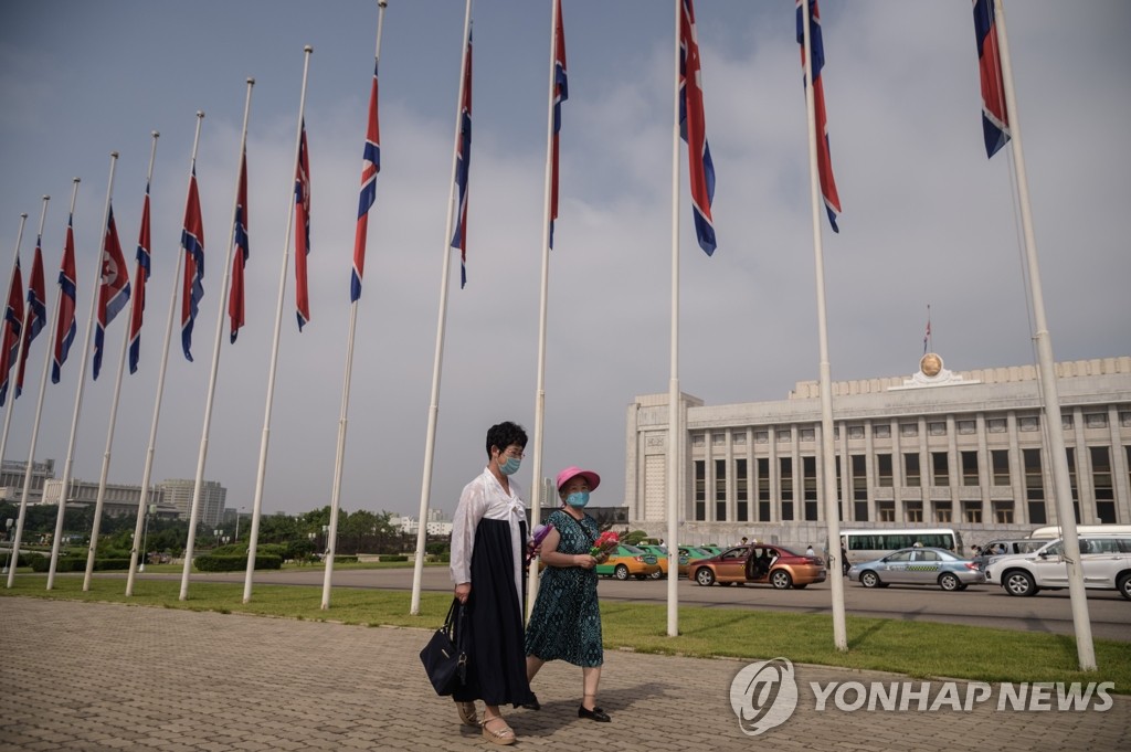 북한 인공기 곁 지나는 주민들