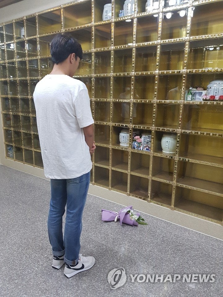 In this photo, provided to Yonhap News Agency by a reader, triathlete Kim Do-hwan stands before an urn containing remains of his late teammate Choi Suk-hyeon to pay his respects at a memorial park in Seongju, 300 kilometers southeast of Seoul, on July 9, 2020. Kim admitted allegations made earlier by Choi that he had physically assaulted her while they were teammates for Gyeonggju City Hall club. (PHOTO NOT FOR SALE) (Yonhap)