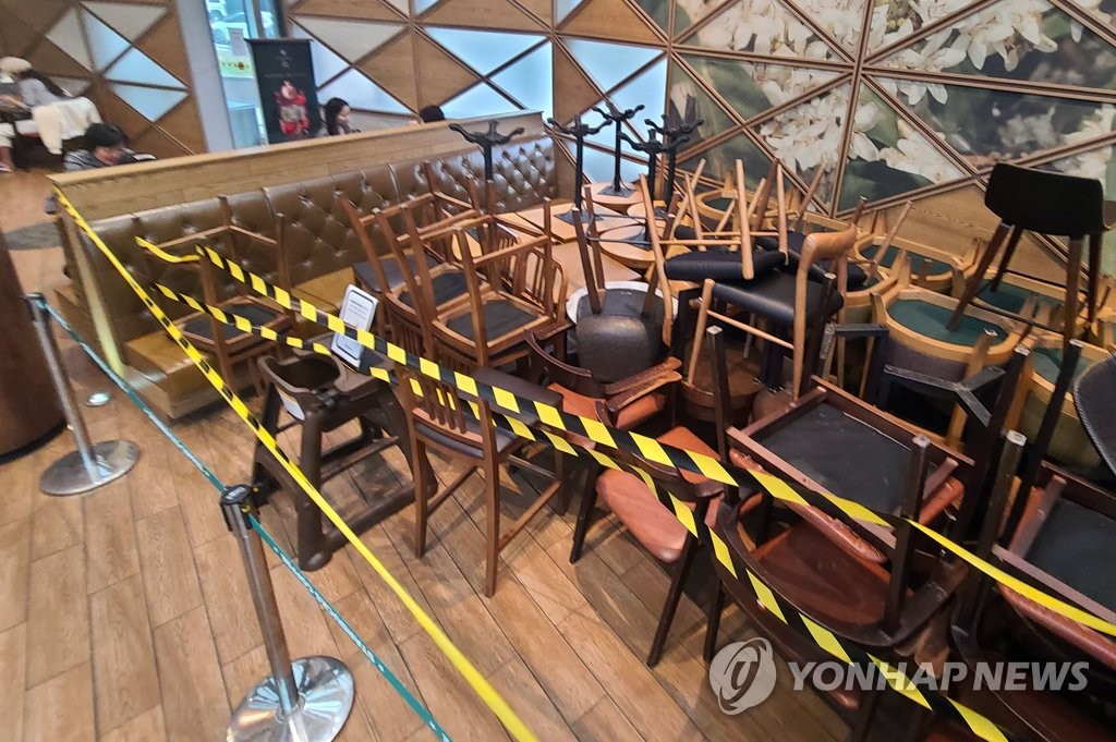 Tables and chairs are piled up at a coffee shop in Seoul on Nov. 18, 2020, a day before tightened social distancing goes into effect. (Yonhap)