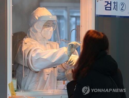A health worker collects a sample from a citizen at a makeshift virus testing clinic in Seoul on Jan. 19, 2021. (Yonhap)