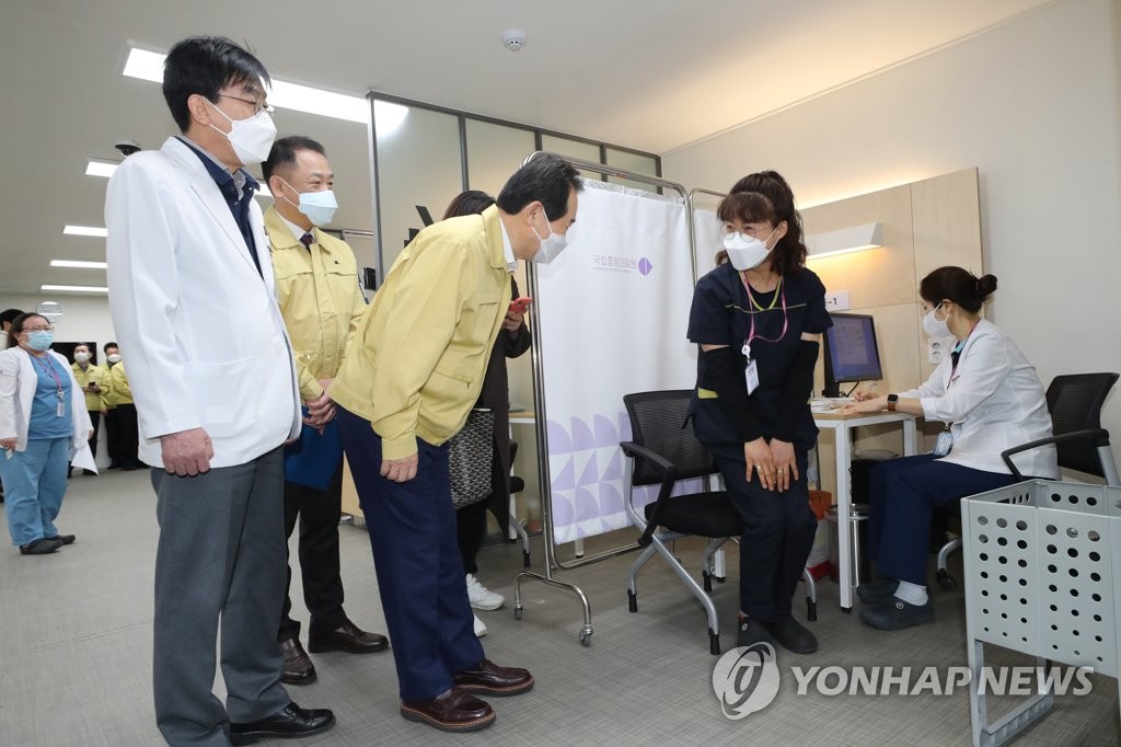 화이자 백신 1호 접종자에게 인사하는 총리