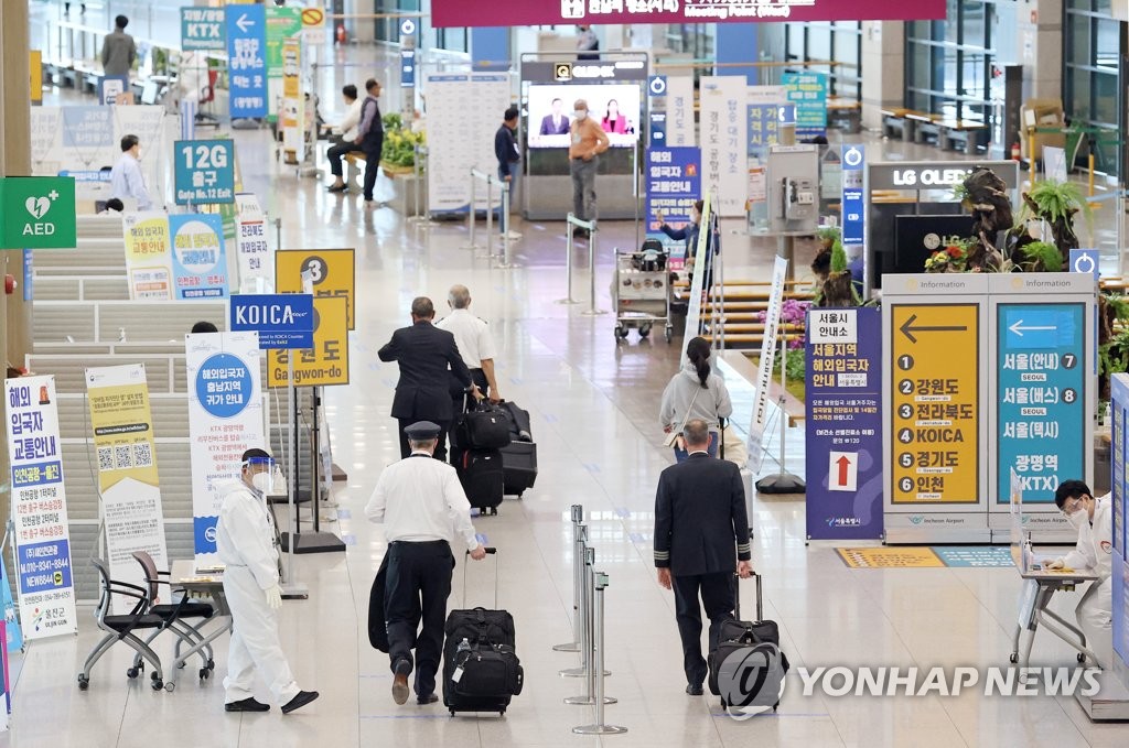 In this file photo taken on April 21, 2021, health workers guide arrivals at Incheon International Airport, west of Seoul. (Yonhap)