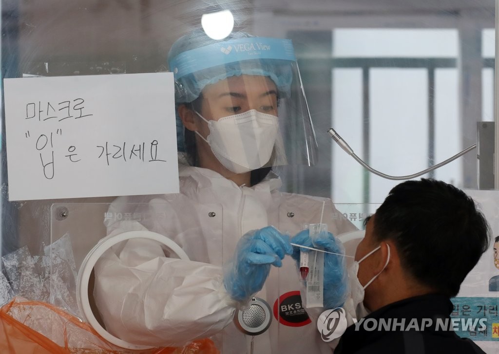 A medical worker collects a sample from a man to test for COVID-19 at a makeshift virus testing center near Seoul Station in Seoul on May 10, 2021. (Yonhap)