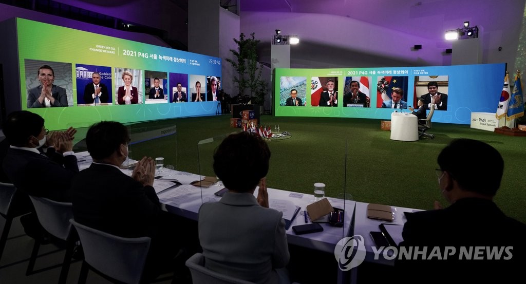 In this file photo taken on May 31, 2021, participants clap as South Korean President Moon Jae-in announces the Seoul Declaration after completing the two-day P4G Seoul Summit at Dongdaemun Design Plaza in Seoul. In the declaration, global leaders committed to efforts to achieve carbon neutrality. (Yonhap)