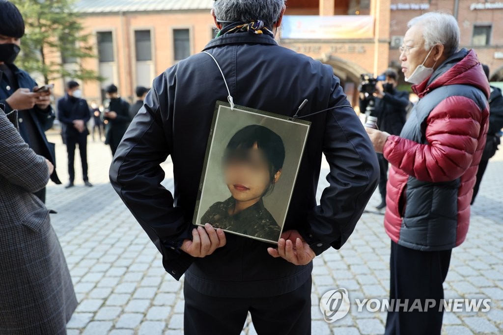 This file photo, taken Nov. 25, 2021, shows the father of a deceased Air Force noncommissioned officer holding a picture of his daughter during a protest in Seoul. The officer took her own life in May after being sexually harassed by a colleague. (Yonhap)