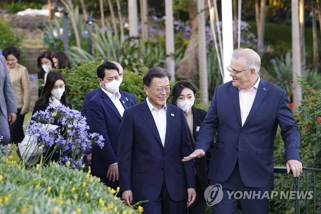 Le président Moon Jae-in, en visite d'Etat en Australie, et le Premier ministre australien Scott Morrison se promènent ensemble avant un dîner officiel à la résidence du second à Sydney, le mardi 14 décembre 2021 (heure locale).