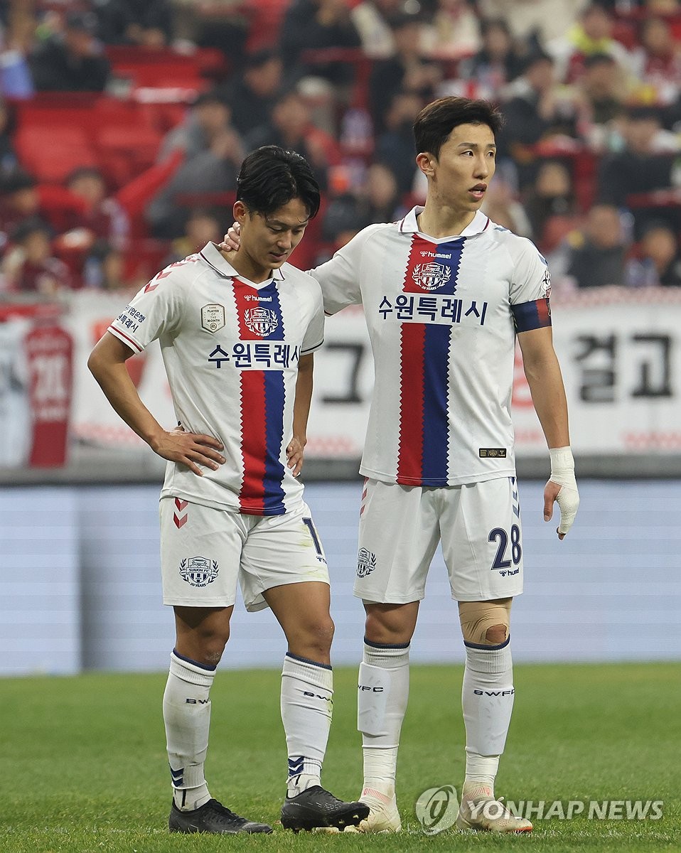 Lee Seung-woo of Suwon FC (L) is consoled by teammate Lee Yeong-jae after picking up his second yellow card of the match against Busan IPark during the opening leg of the K League promotion-relegation playoffs at Busan Asiad Main Stadium in the southeastern city of Busan on Dec. 6, 2023. (Yonhap)