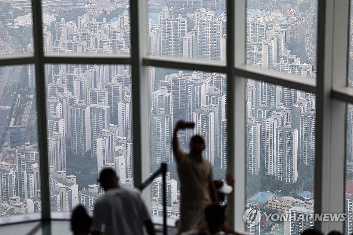 People take photos of apartments in Seoul on July 6, 2025. (Yonhap)